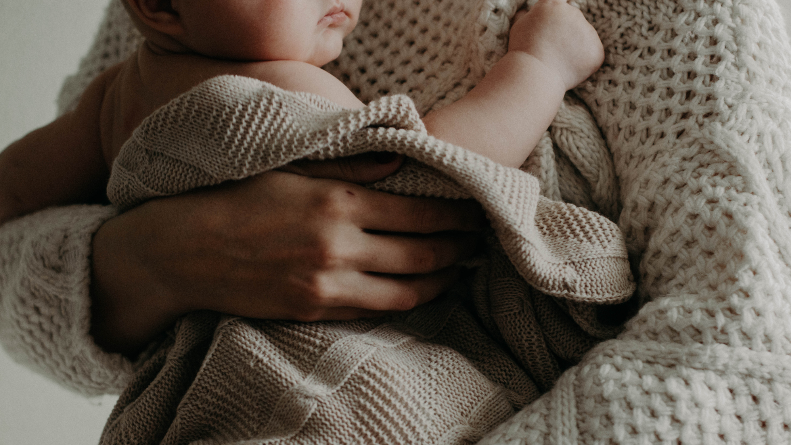 Mutter hält Baby im Arm mit einer Wolldecke